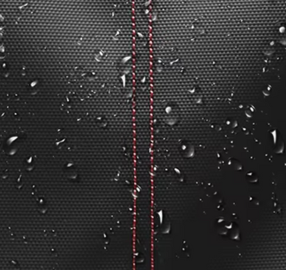 Close-up of waterproof black travel backpack fabric with red stitching and water droplets